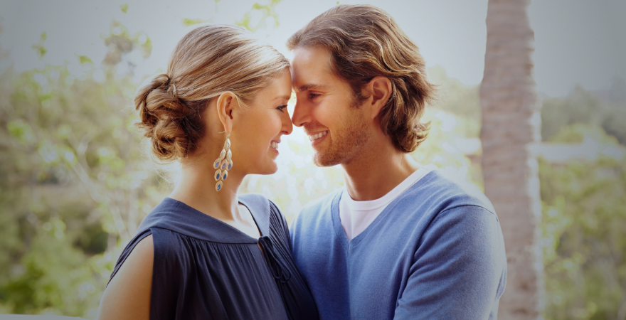 Young couple faces each other smiling. 
